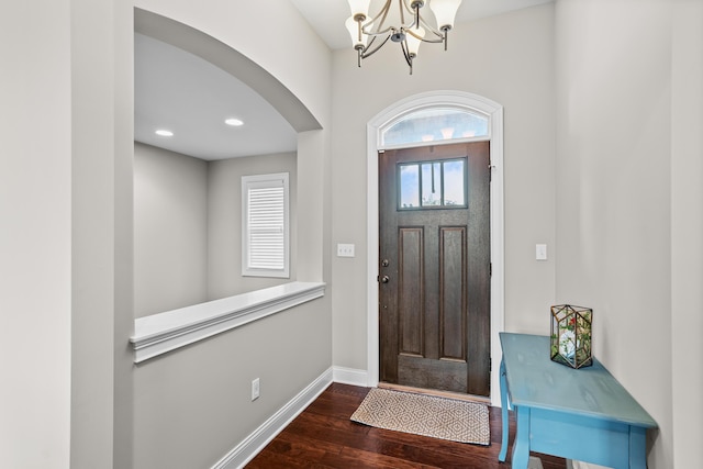 entrance foyer with arched walkways, recessed lighting, baseboards, dark wood finished floors, and an inviting chandelier