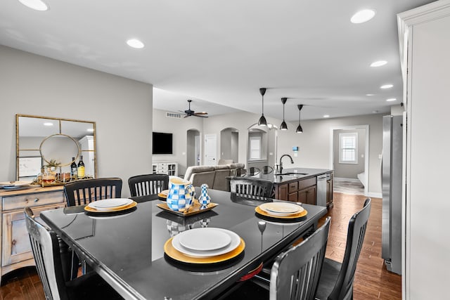 dining room featuring dark wood-style floors, arched walkways, a ceiling fan, and recessed lighting