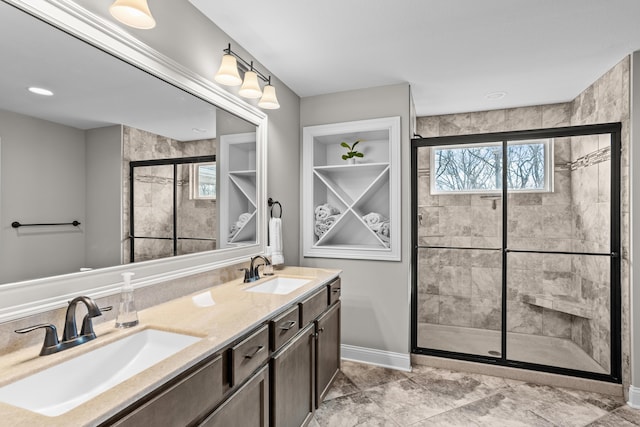 full bathroom with double vanity, a shower stall, and a sink