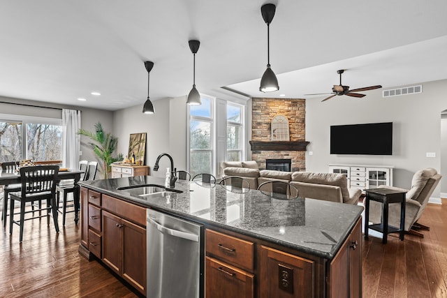 kitchen featuring a sink, visible vents, hanging light fixtures, dishwasher, and dark stone countertops