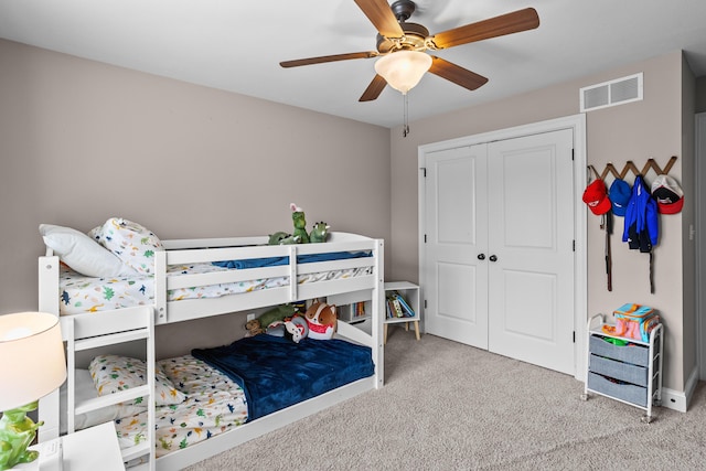 bedroom featuring ceiling fan, visible vents, a closet, and light colored carpet