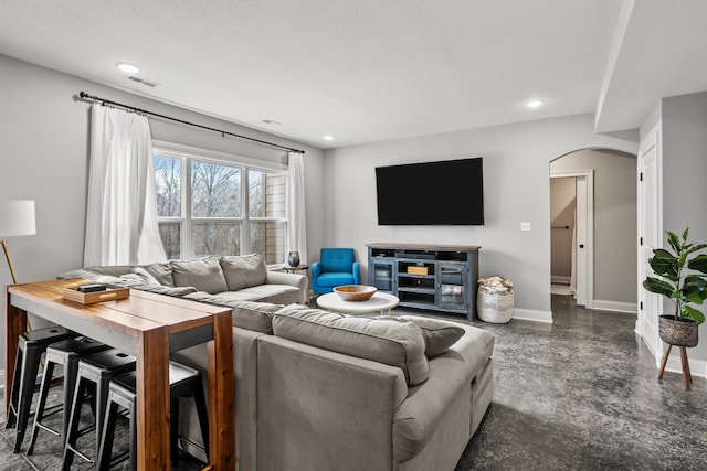 living area with arched walkways, recessed lighting, visible vents, and baseboards