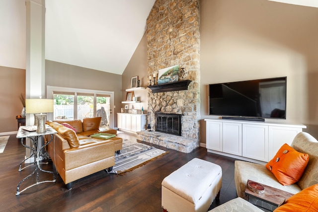 living room with high vaulted ceiling, a stone fireplace, baseboards, and wood finished floors