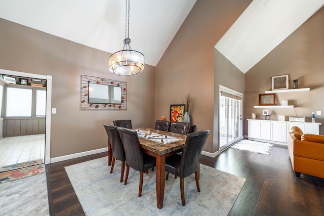 dining space featuring dark wood-type flooring, high vaulted ceiling, baseboards, and an inviting chandelier