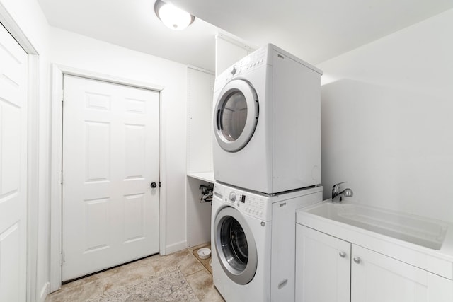 clothes washing area with cabinet space and stacked washer / drying machine