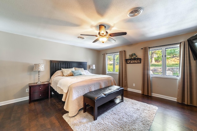 bedroom featuring baseboards, a textured ceiling, visible vents, and dark wood-type flooring