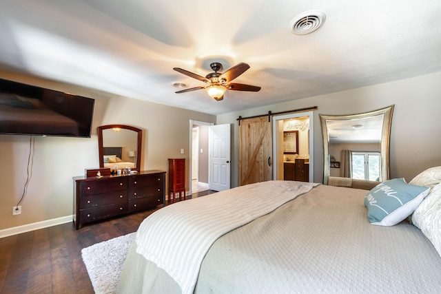 bedroom featuring a barn door, baseboards, visible vents, ceiling fan, and wood finished floors