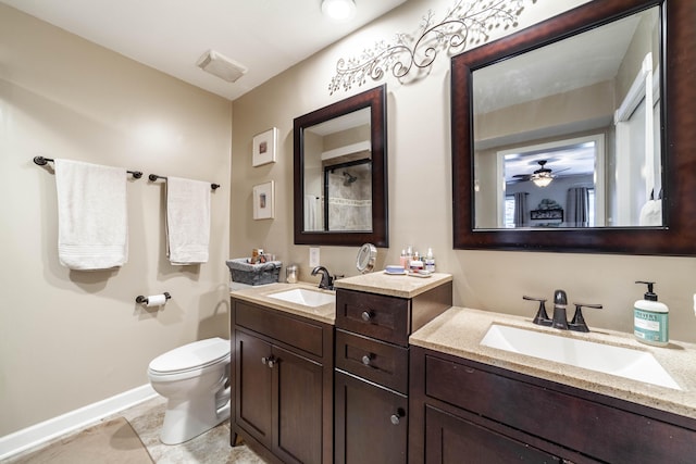 full bath featuring baseboards, a sink, toilet, and double vanity