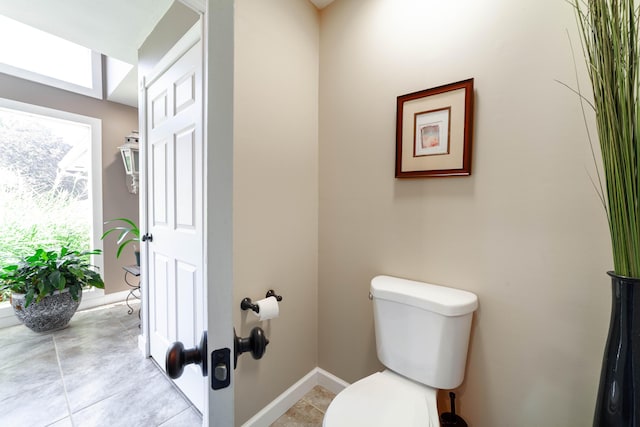 bathroom featuring tile patterned flooring, baseboards, and toilet