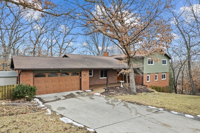 split level home with an attached garage, driveway, a chimney, and brick siding