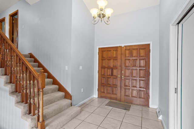 entrance foyer featuring light tile patterned floors, baseboards, stairs, and an inviting chandelier