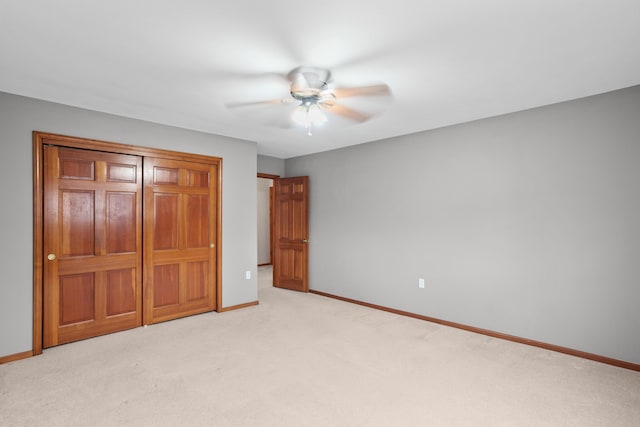 unfurnished bedroom with a ceiling fan, a closet, light colored carpet, and baseboards