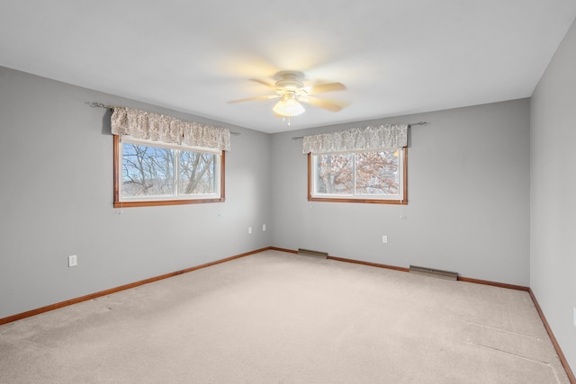 carpeted empty room featuring a ceiling fan, visible vents, and baseboards