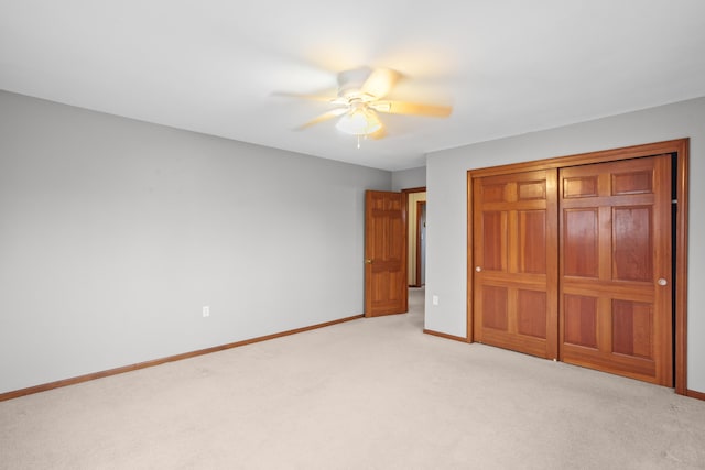 unfurnished bedroom featuring light carpet, ceiling fan, a closet, and baseboards