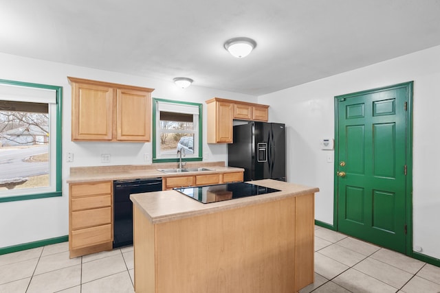 kitchen with a sink, light countertops, light brown cabinetry, a center island, and black appliances