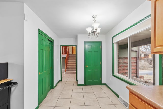 entrance foyer featuring baseboards, visible vents, stairway, a notable chandelier, and light tile patterned flooring