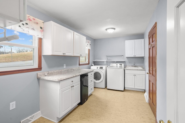 washroom with a healthy amount of sunlight, visible vents, a sink, and washing machine and clothes dryer