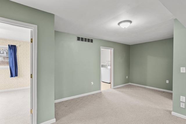 unfurnished room with washer / clothes dryer, visible vents, light carpet, and baseboards