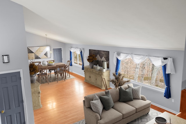 living area with vaulted ceiling, baseboards, and light wood-style floors