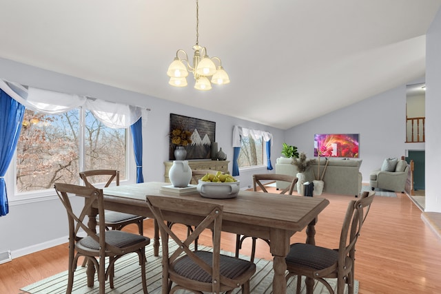 dining room featuring light wood-style flooring, a notable chandelier, visible vents, baseboards, and vaulted ceiling