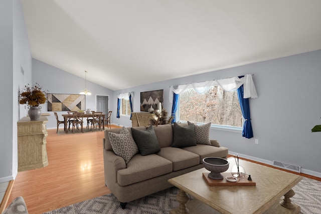 living room with lofted ceiling, visible vents, plenty of natural light, and wood finished floors