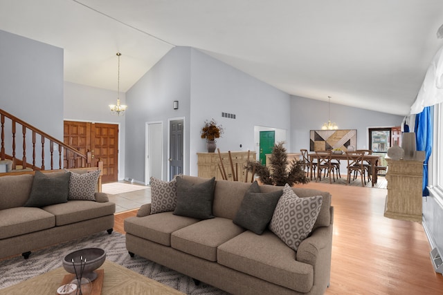 living area featuring stairs, light wood-type flooring, visible vents, and a notable chandelier