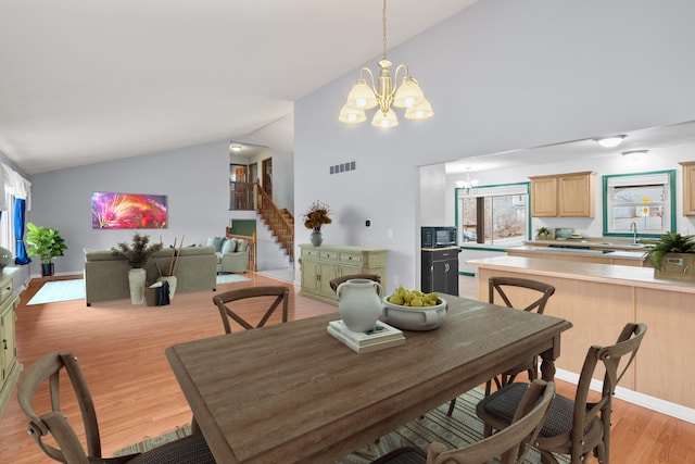 dining area with light wood finished floors, visible vents, stairway, high vaulted ceiling, and a notable chandelier