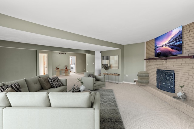 carpeted living area with washer / clothes dryer, a brick fireplace, visible vents, and baseboards