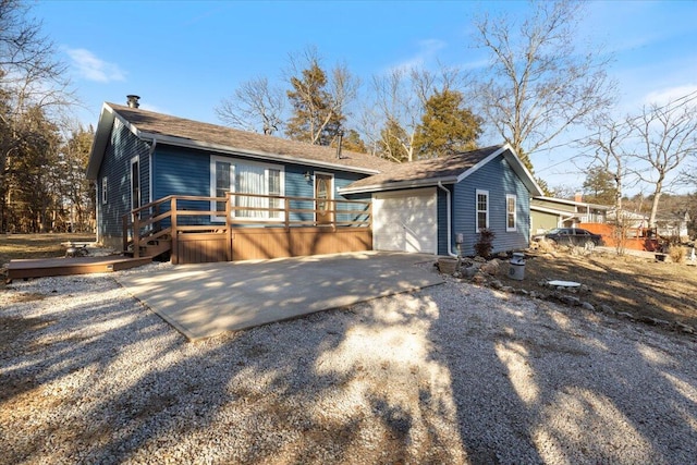 view of front facade featuring a garage, driveway, a deck, and an outdoor structure