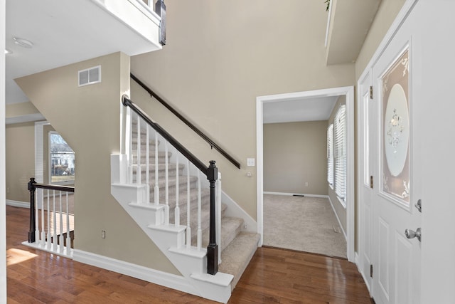 entrance foyer with a wealth of natural light, visible vents, baseboards, and wood finished floors