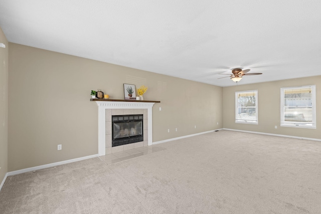 unfurnished living room with light carpet, baseboards, and a tiled fireplace