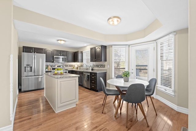 kitchen featuring stainless steel appliances, light wood-style floors, a sink, and tasteful backsplash