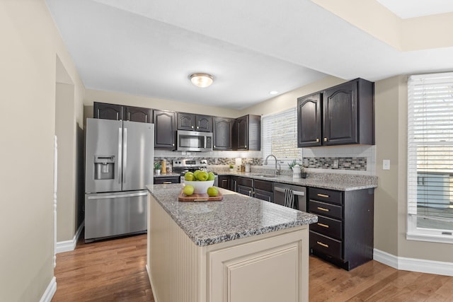 kitchen featuring light wood-style flooring, appliances with stainless steel finishes, backsplash, and a sink