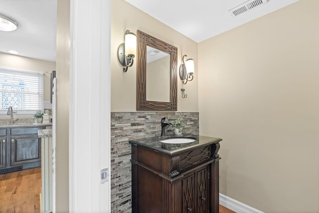 bathroom with visible vents, backsplash, vanity, wood finished floors, and baseboards