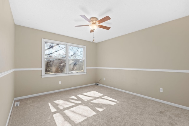 unfurnished room with carpet floors, visible vents, baseboards, and a ceiling fan