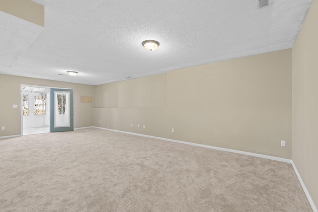 carpeted spare room with baseboards, visible vents, and a textured ceiling