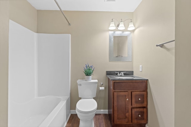 bathroom featuring toilet, baseboards, wood finished floors, and vanity