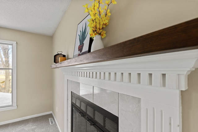 room details featuring a textured ceiling, carpet floors, visible vents, and baseboards