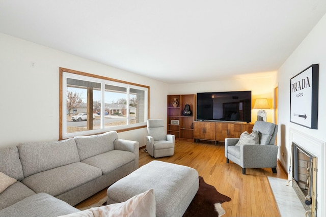 living area featuring a fireplace with flush hearth and light wood finished floors