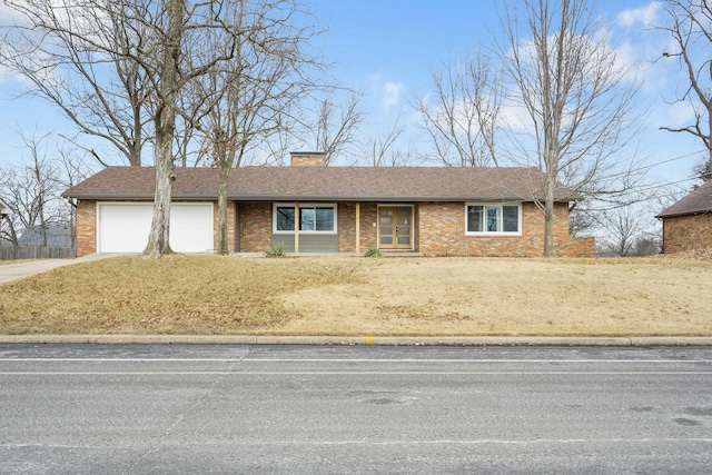 ranch-style house with concrete driveway, brick siding, a chimney, and an attached garage