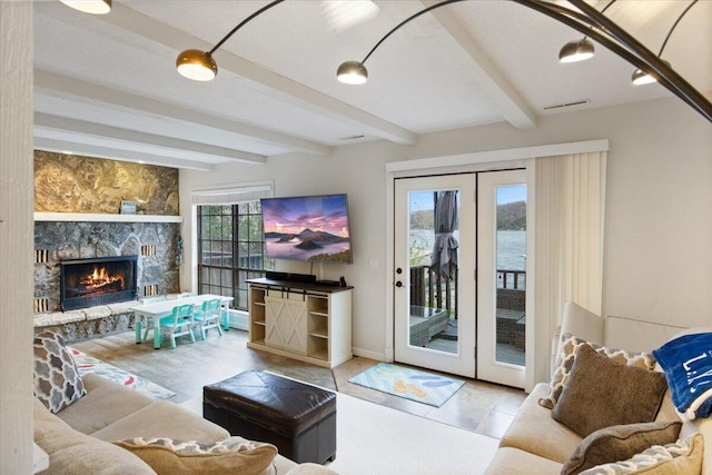 living room featuring visible vents, french doors, beamed ceiling, and a stone fireplace