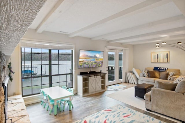 living room featuring french doors, a fireplace, beam ceiling, and wood finished floors