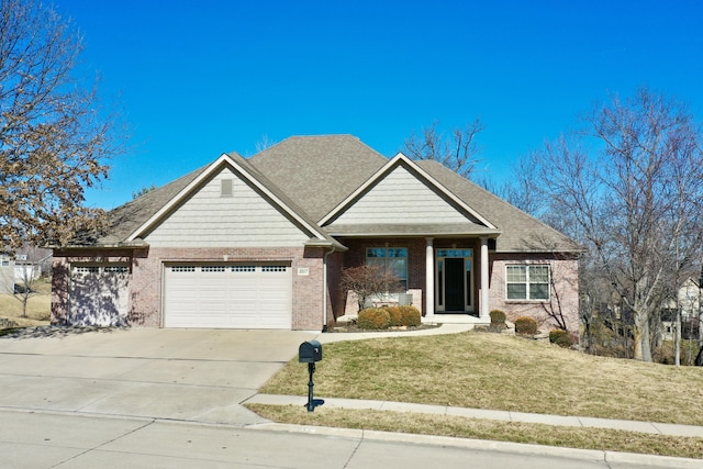 craftsman house with an attached garage, brick siding, driveway, and a front yard