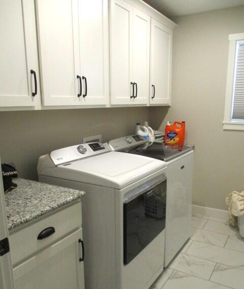 laundry room with marble finish floor, cabinet space, washer and clothes dryer, and baseboards