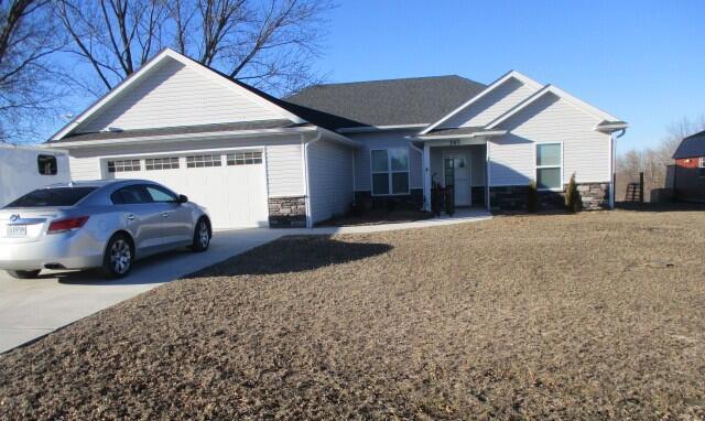 view of front of property featuring a garage, stone siding, and driveway