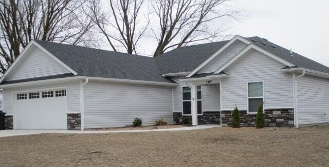 craftsman-style house with concrete driveway, an attached garage, and stone siding