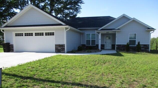 305 E Francis St, Sturgeon, MO 65284 - craftsman-style house featuring a garage, stone siding, a front yard, and concrete driveway
