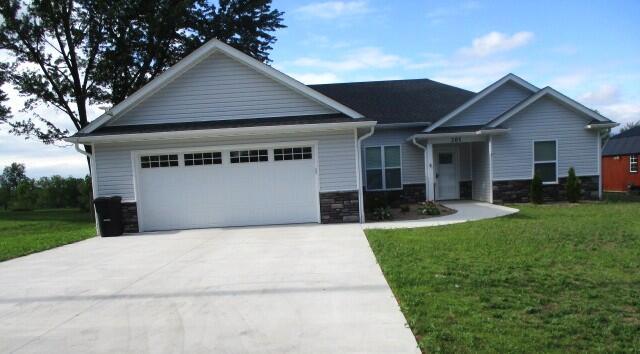 305 E Francis St, Sturgeon, MO 65284 - craftsman-style house with a garage, concrete driveway, stone siding, and a front yard