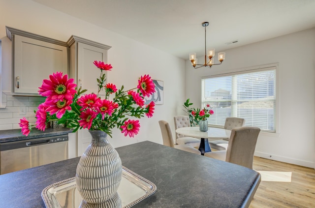 dining room featuring light wood finished floors, baseboards, visible vents, and a chandelier