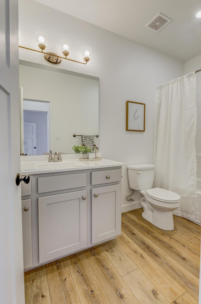 full bath with visible vents, vanity, toilet, and hardwood / wood-style flooring